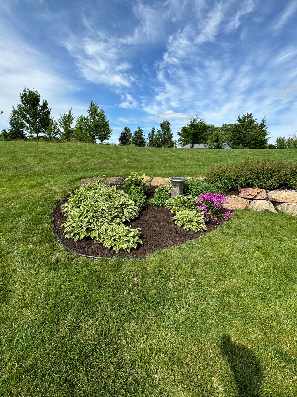 Lush garden landscape featuring colorful flowers, greenery, and a decorative stone border.