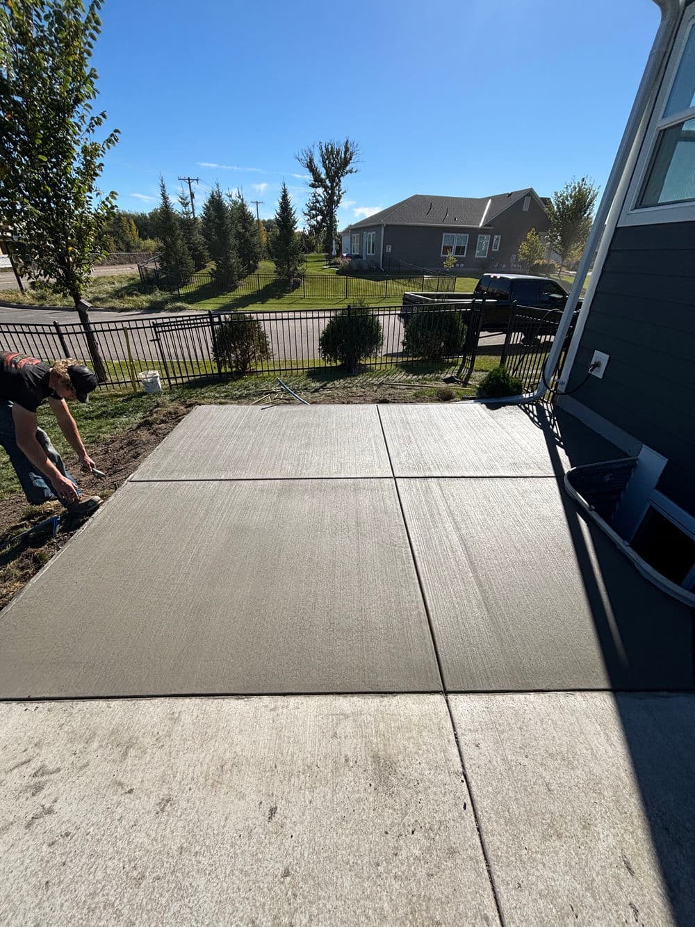Concrete patio installation in progress, showcasing fresh concrete slabs and surrounding landscaping.