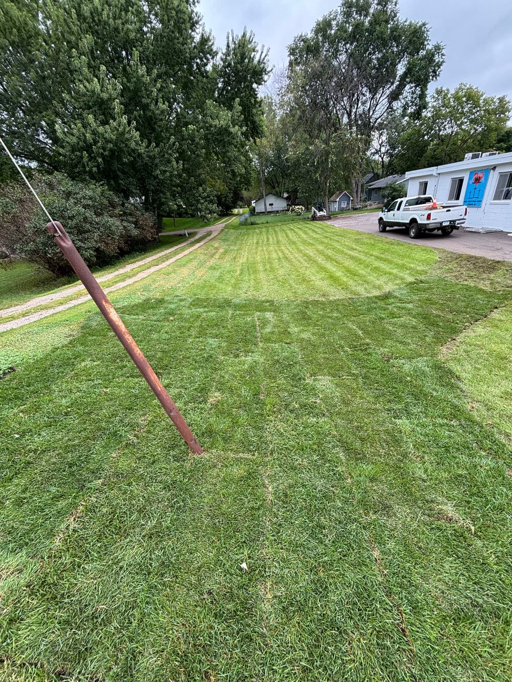 Freshly mowed lawn with clearly defined stripes and a parked white truck nearby.