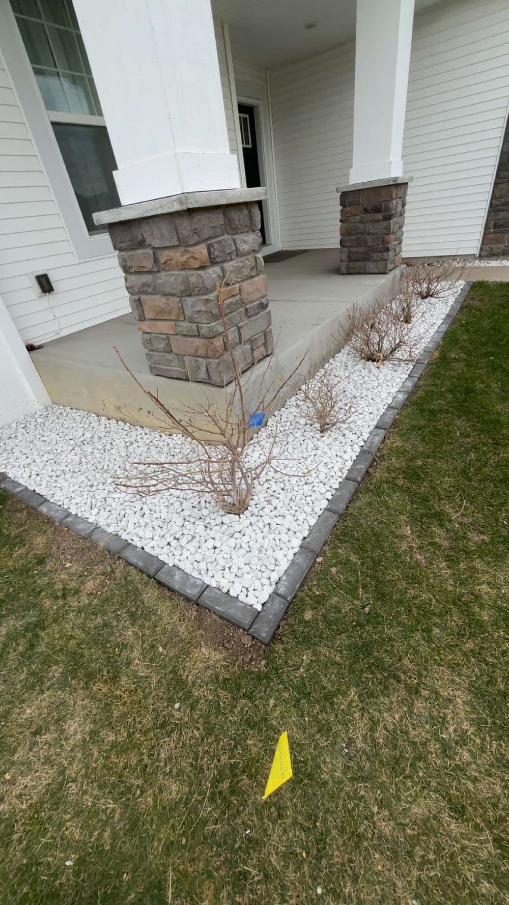 Landscaped front porch with stone borders, white gravel, and low shrubs.